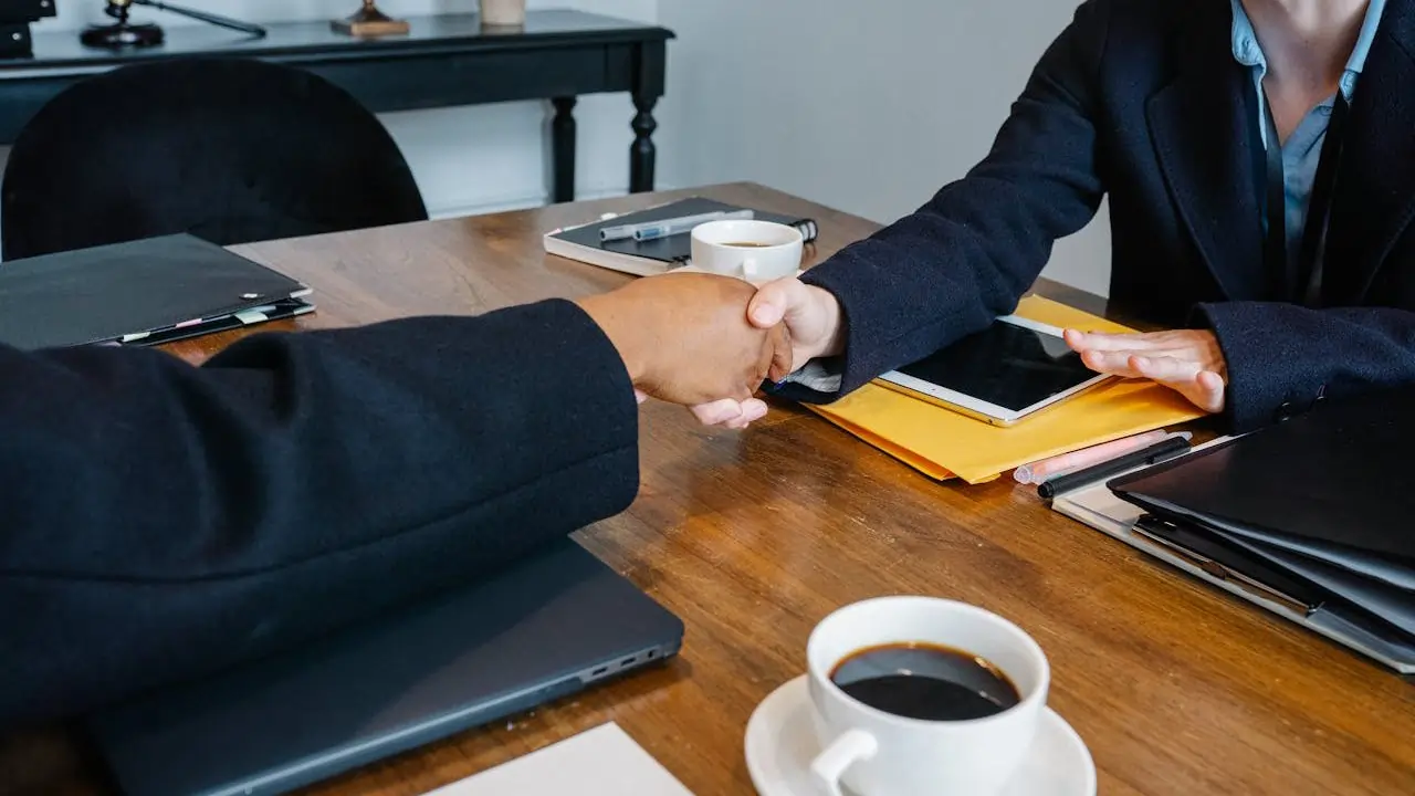 Two business professionals shaking hands over a conference table