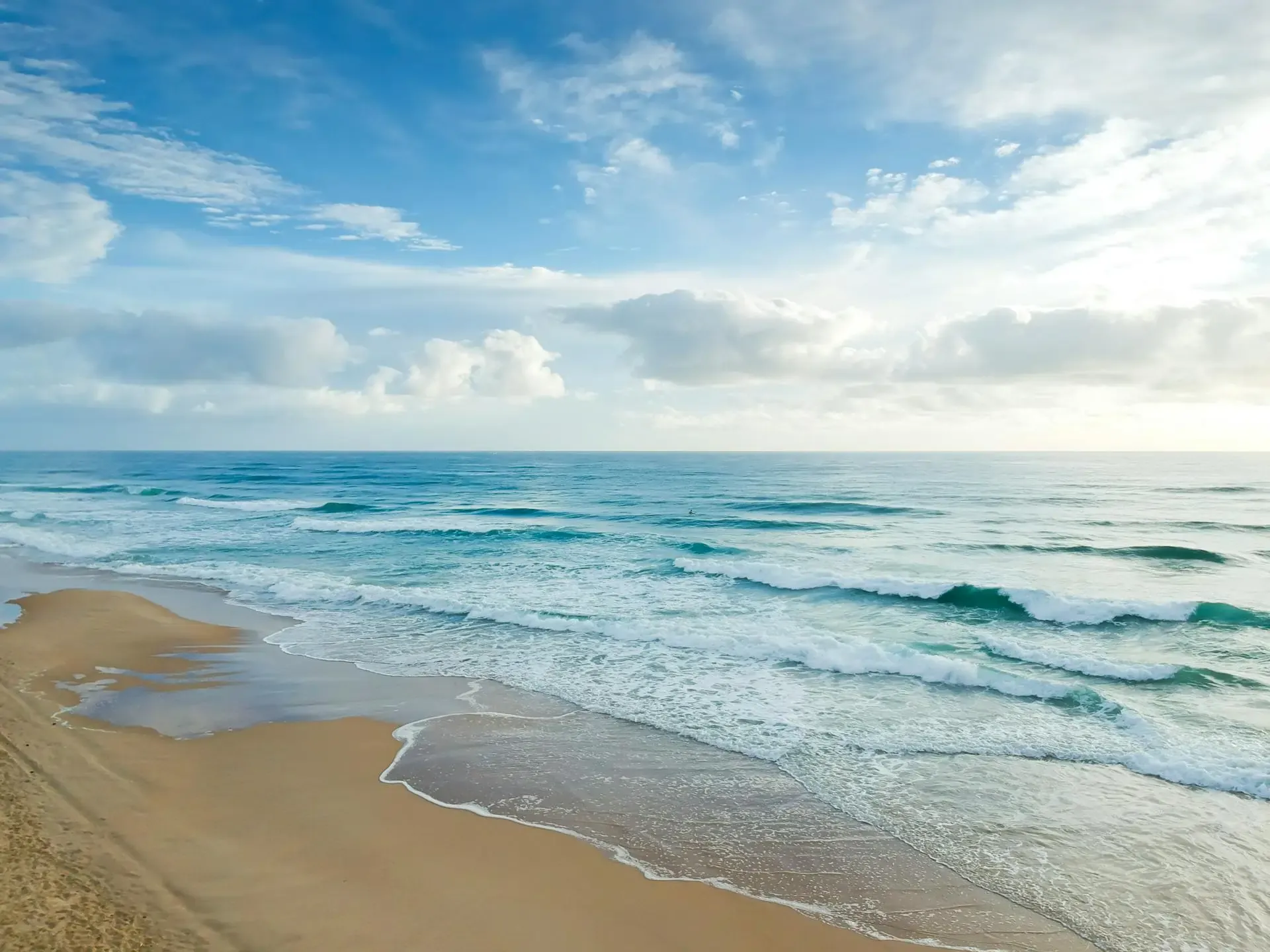 A serene beach scene featuring gentle waves lapping against golden sand under a clear blue sky