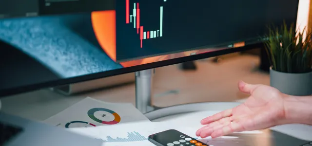 a person pointing at a calculator on a desk by Jakub Żerdzicki courtesy of Unsplash.